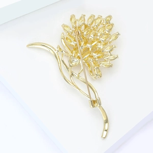 Detail of flower brooch with yellow zircon stones and gold-plated pin on white background