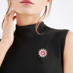 Broche tournesol avec pétales en zircon rose et perle sur un pull noir élégant