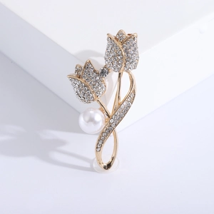 Broche tulipe dorée avec strass scintillants et perle blanche sur support géométrique blanc