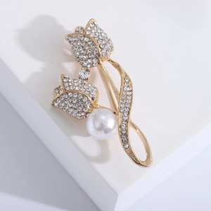 Gros plan sur la broche tulipe avec strass pavés et perle blanche sur finition dorée