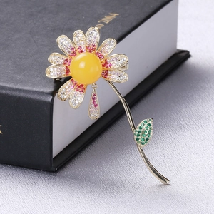 Elegant daisy flower brooch with yellow gemstone and micro-paved crystals on a book