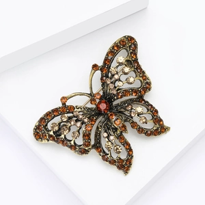 Detail of vintage butterfly brooch with amber rhinestones on a white display stand