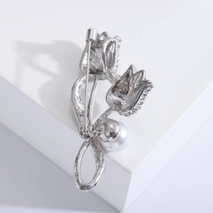 Détail macro d'une broche tulipe avec strass pavés et une grande perle blanche