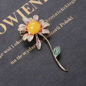 Detail of sunflower brooch with sparkling cubic zirconia and yellow center on a book