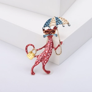 Cute red enamel cat brooch with umbrella and handbag on a white geometric stand