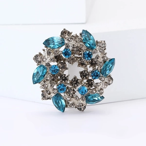 Detailed close-up of a floral wreath brooch featuring blue and smoky grey crystal rhinestones