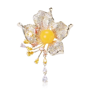 Detailed shot of flower brooch with yellow gemstone and zircon tassels on gold setting
