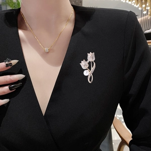 Élégante broche tulipe en or avec des oxydes de zirconium et une grande perle sur un manteau