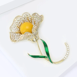 Broche camélia dorée élégante avec pierre jaune et strass blancs sur fond blanc épuré