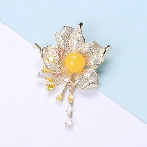 Detailed close-up of a floral brooch featuring yellow amber center and zircon tassel accents