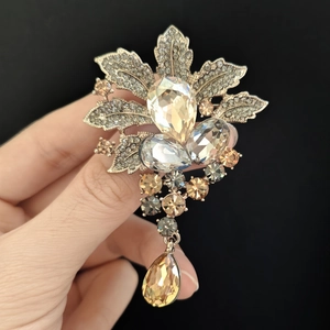 Macro detail of maple leaf brooch with sparkling crystals and amber water drop pendant