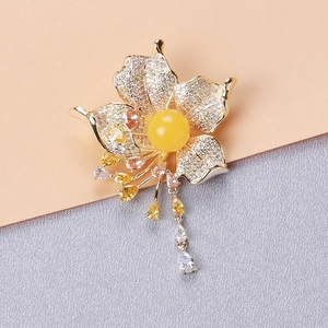 Close-up of floral brooch with amber center and sparkling zircon tassels on soft fabric