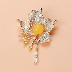 Detailed close-up of a luxury gold flower brooch with zircon tassels and amber-like stone