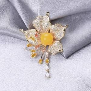 Detail of flower brooch with gold petals, amber center stone and hanging gemstone tassels