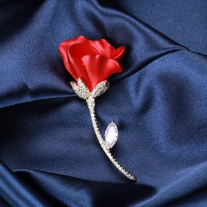 Gros plan d'une broche rose rouge avec zircons sertis sur un tissu en soie bleu marine