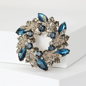 Macro view of crystal wreath brooch featuring dark blue and smoke grey gemstones