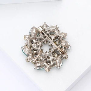 Detail view showing the metal alloy back and secure pin clasp of the floral wreath brooch