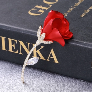 Vue détaillée d'une broche rose avec pétales rouges et zircons blancs sur or