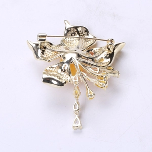 Detail view of the floral brooch back showing gold-plated metal base and safety pin clasp