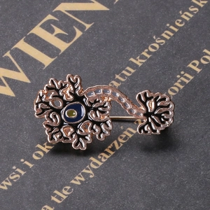 Macro shot of gold-plated neuron brooch with dark blue enamel on a vintage book