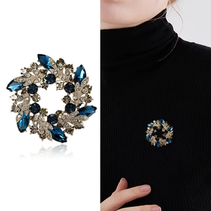 Baroque crystal flower wreath brooch in deep blue and gold on a white background