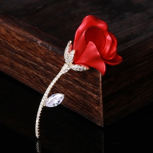 Broche rose élégante avec pétales rouges mats et zircons sur fond de bois sombre