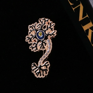 Detailed macro view of an enamel neuron brooch with golden frame and colorful accents