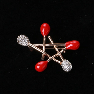 Star-shaped matchstick brooch with red enamel and white crystals on black background