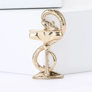 Vintage gold snake and cup brooch pin for suits with polished finish on white pedestal