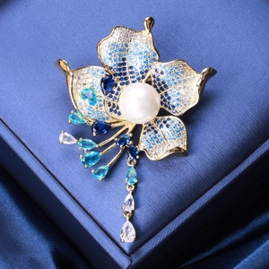 Detail of luxury flower brooch with blue zircons, large pearl and golden fringe