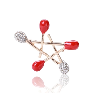 Close-up of gold matchstick star brooch with red enamel tips and sparkling rhinestones