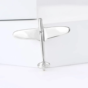 Close-up of minimalist silver airplane brooch with polished mirror finish on white background