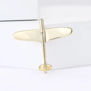 Minimalist polished gold airplane brooch on a modern geometric white background