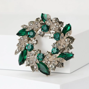 Detailed close-up of emerald green marquise crystals on a silver baroque garland brooch