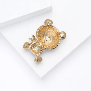 Detailed back view of the golden bear brooch showing the textured alloy surface and pin clasp