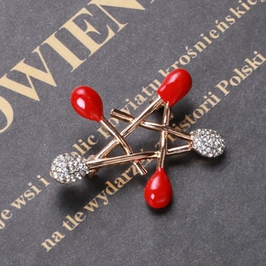 Detail of star brooch with red enamel tips and sparkling rhinestones on golden alloy