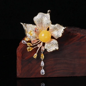 Macro detail of luxury flower brooch with amber center and sparkling zircon tassels