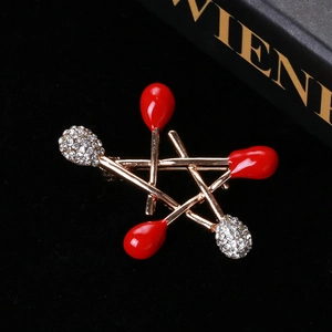 Close-up of gold star matchstick brooch with red enamel and sparkling rhinestones