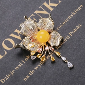 Macro shot of luxury zircon flower brooch with honey amber center and crystal tassels