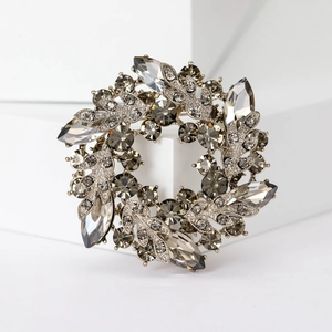 Macro shot of silver crystal brooch with grey marquise gems on white geometric block