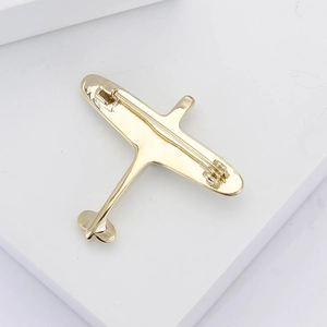 Detailed back view of a golden airplane brooch with a secure metal safety pin closure