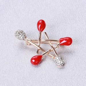 Detailed view of alloy star brooch featuring gold matchsticks with red enamel and rhinestones