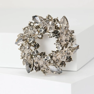 Detailed view of silver wreath brooch with smoky marquise crystals on a white pedestal