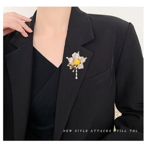 Luxurious flower brooch with yellow gemstone, zircon pavé petals and tassels on a black suit