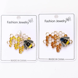 Detailed view of enamel bee brooches with honeycomb patterns and inlaid rhinestones