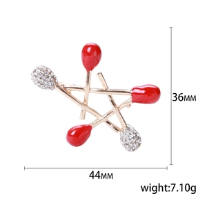 Star-shaped matchstick brooch with sparkling crystals and red enamel detailing