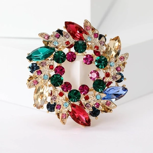 Macro shot of luxury crystal wreath brooch with colorful gemstones and golden floral detail