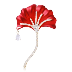 Detail of red ginkgo leaf brooch with gold diamond-encrusted stem and crystal pendant