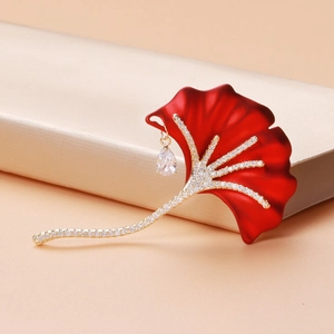 Elegant ginkgo leaf brooch with red enamel and pavé zircon stones on a gold gift box