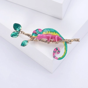 Détails d'une broche caméléon colorée sur une branche avec des feuilles en émail vert